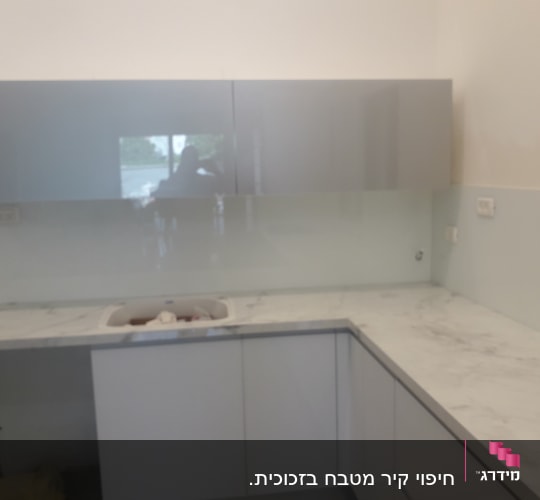 זכוכית שקופה על קיר מטבח מעל השיש